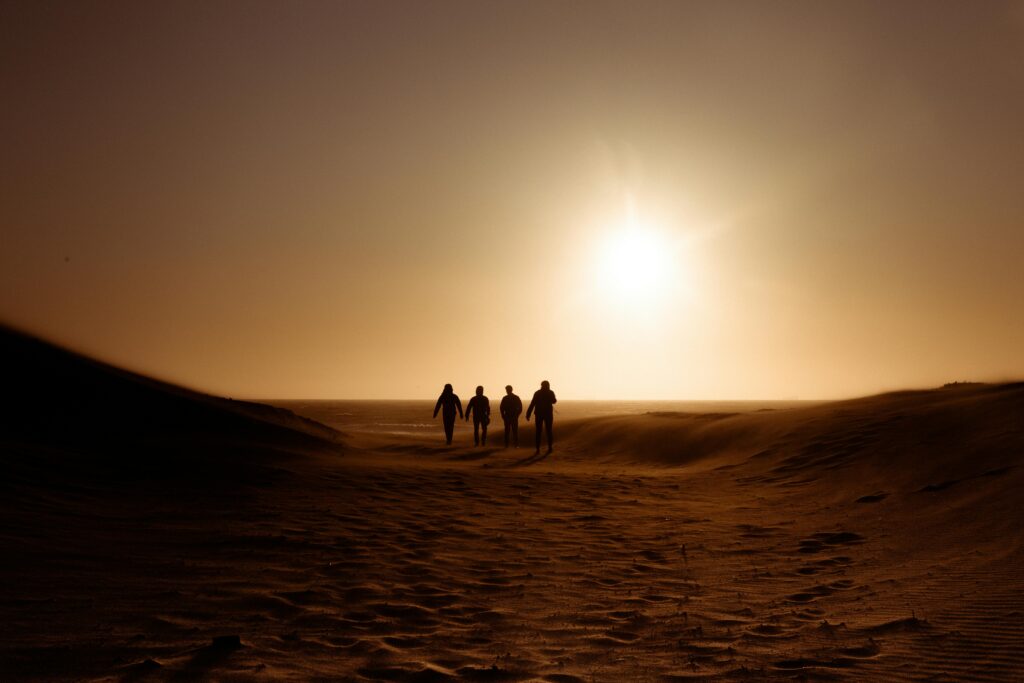 pexels-photo-3006007-3006007 Familienkonflikte, Silhouettes of people walking on sand dunes during a picturesque sunset in a desert landscape.